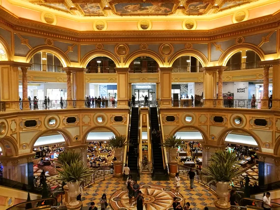 Ornate golden interior of the Venetian Macao casino with arched columns and escalators