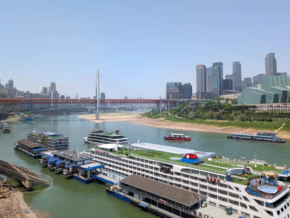 Cruise ships and ferries docked on the Yangtze River in Chongqing with cable-stayed bridge behind