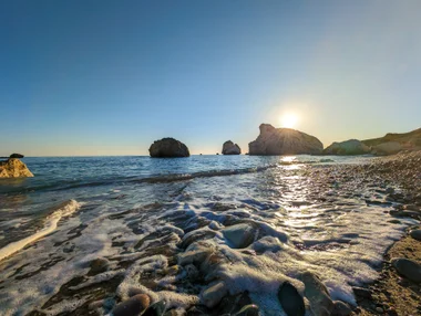 Petra tou Romiou at sunset with waves on the pebble beach