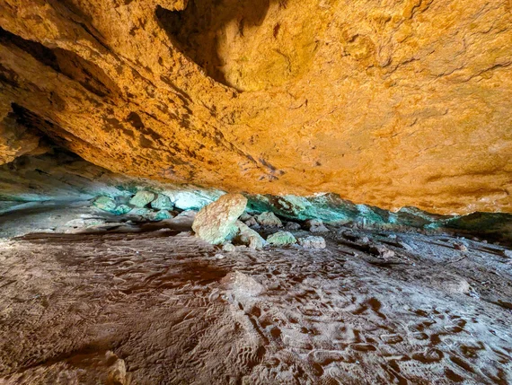 Inside a golden-ceilinged sea cave with mineral deposits