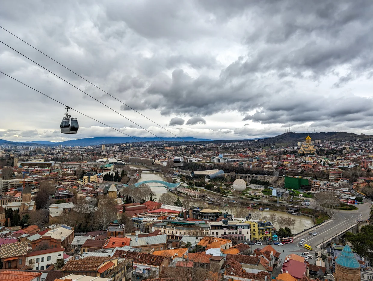 Tbilisi from the cable car: the city, the river, the Bridge of Peace, Trinity Cathedral visible in the distance