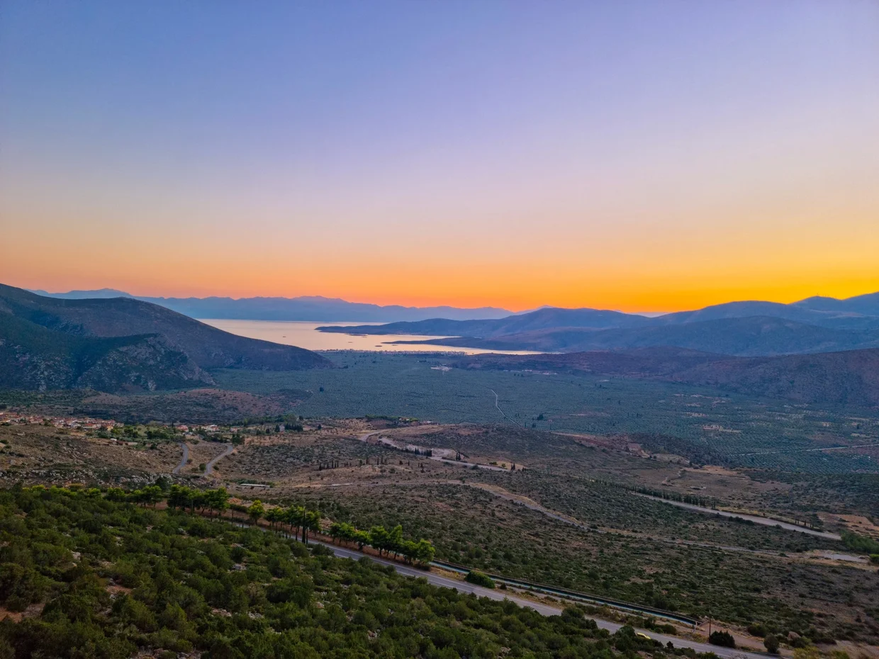 Golden sunset over the valley below Delphi with the Gulf of Corinth in the distance
