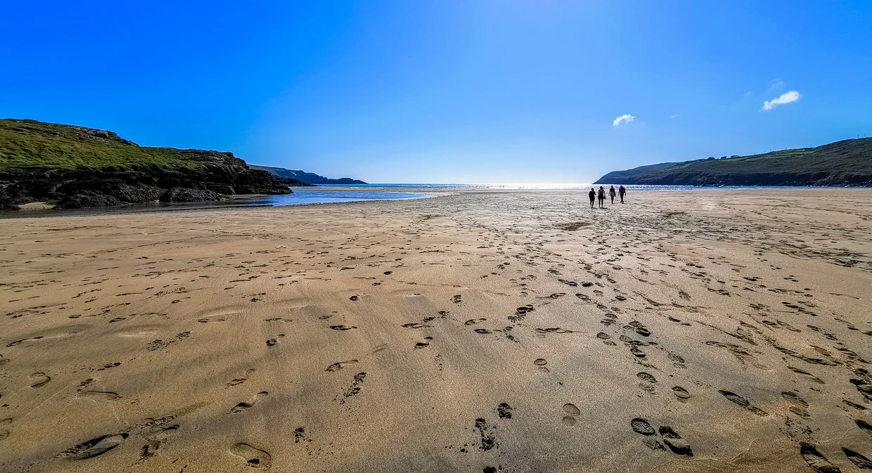 Footprints in the sand stretching across a sheltered beach near Mizen Head at low tide
