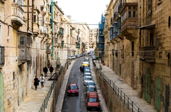 Steep narrow street with enclosed balconies and parked cars