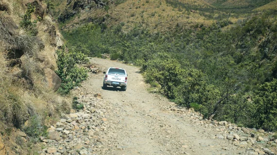 White pickup truck navigating a rocky dirt road on the Sani Pass descent