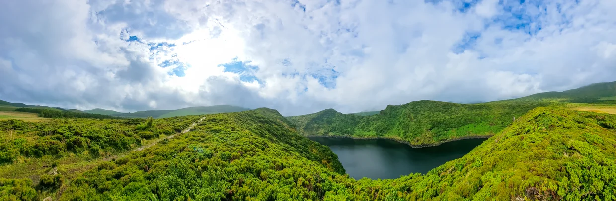Panoramic view of a volcanic crater lake surrounded by green hills