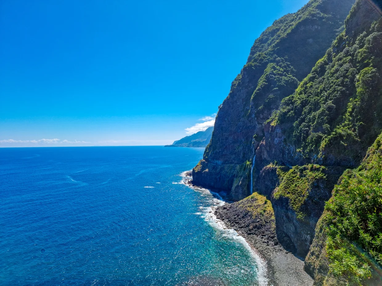 Towering sea cliff with a waterfall streaming into the ocean, north coast