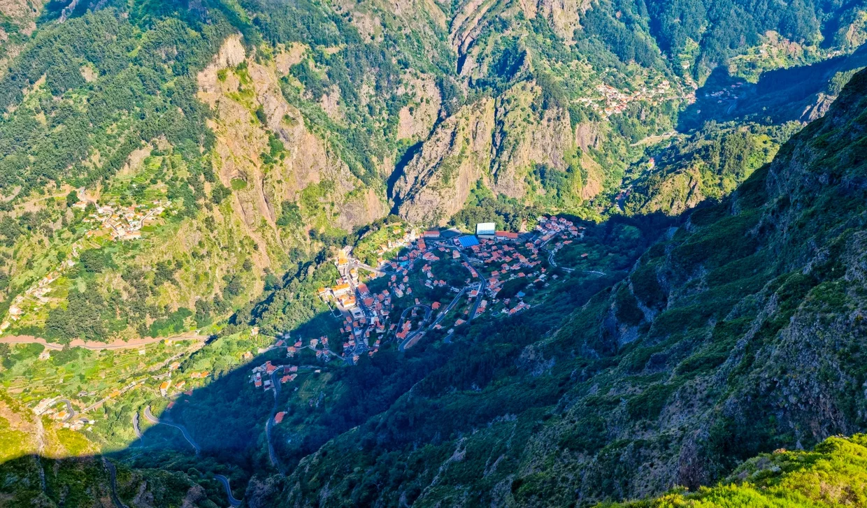 Curral das Freiras village far below, nestled at the bottom of an immense mountain valley