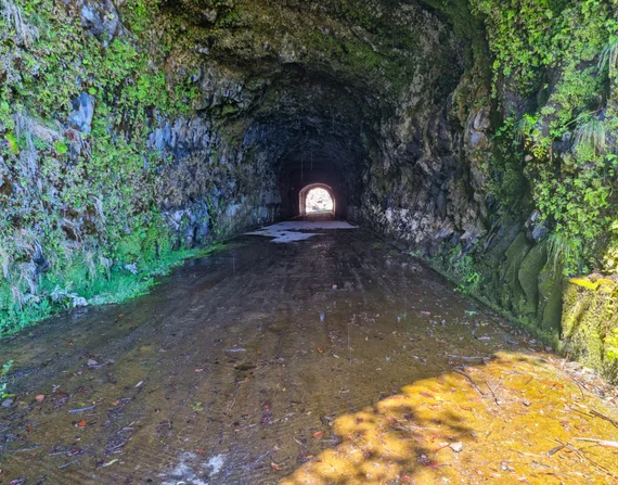 Inside a levada tunnel, wet stone floor, light ahead