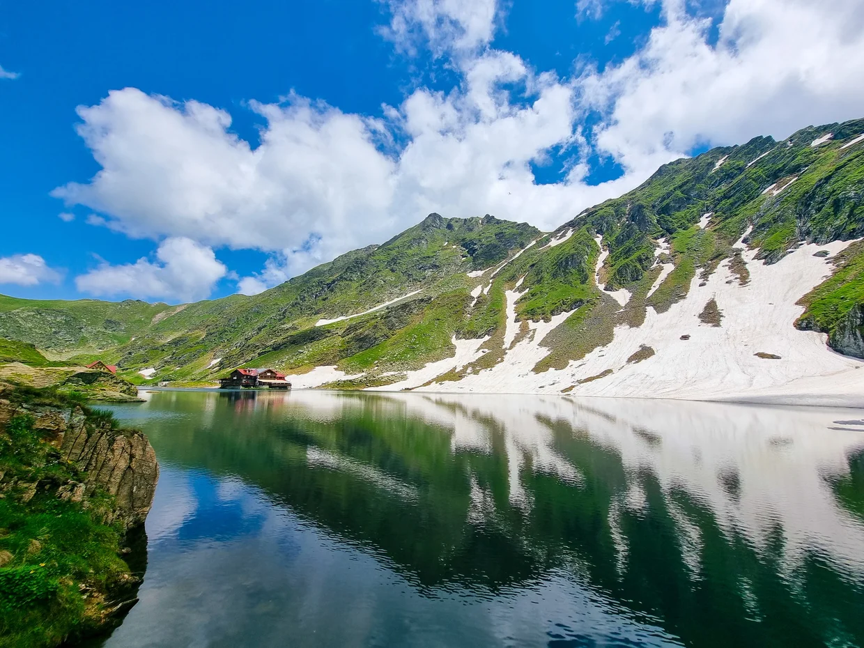 The Bâlea Lake shoreline with snow and mountain slopes