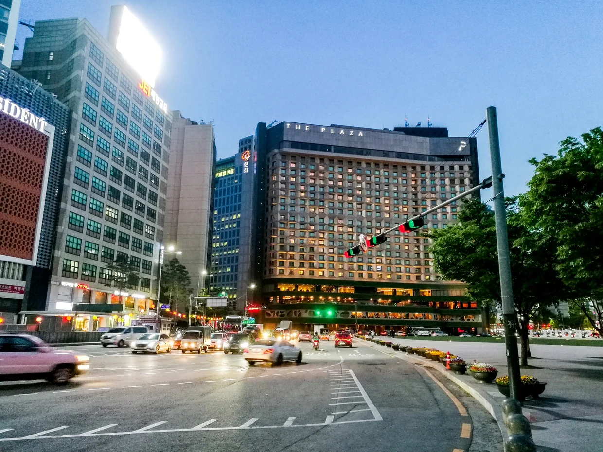 The Plaza Hotel and busy intersection at dusk near City Hall