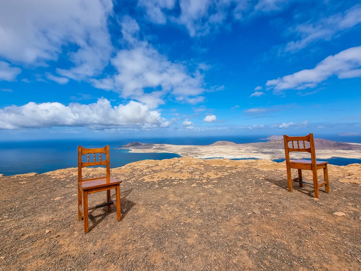 Two chairs at a viewpoint overlooking La Graciosa island and the ocean