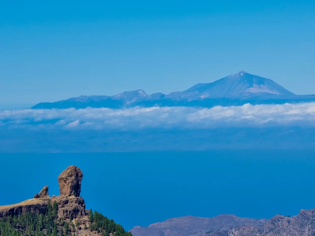 Roque Nublo rock formation with Teide on Tenerife floating above clouds across the sea