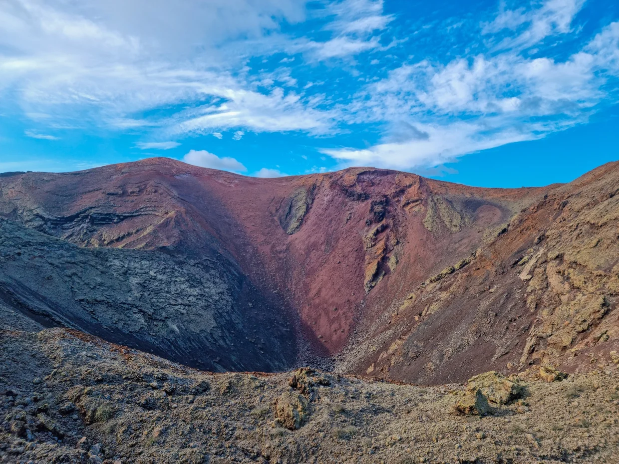Close view of volcano crater interior, vivid red, brown, and black mineral colors