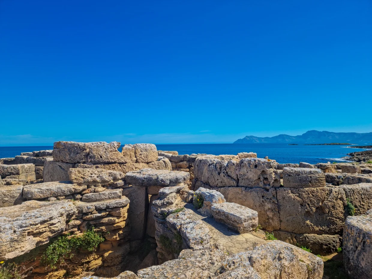 Ancient stone ruins by the sea, mountains on horizon