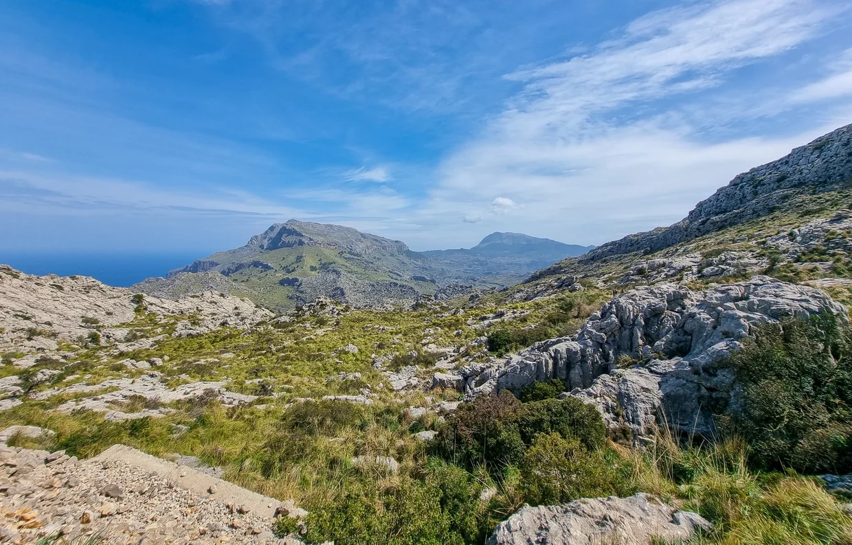 Rocky karst terrain with mountain peaks and distant ocean