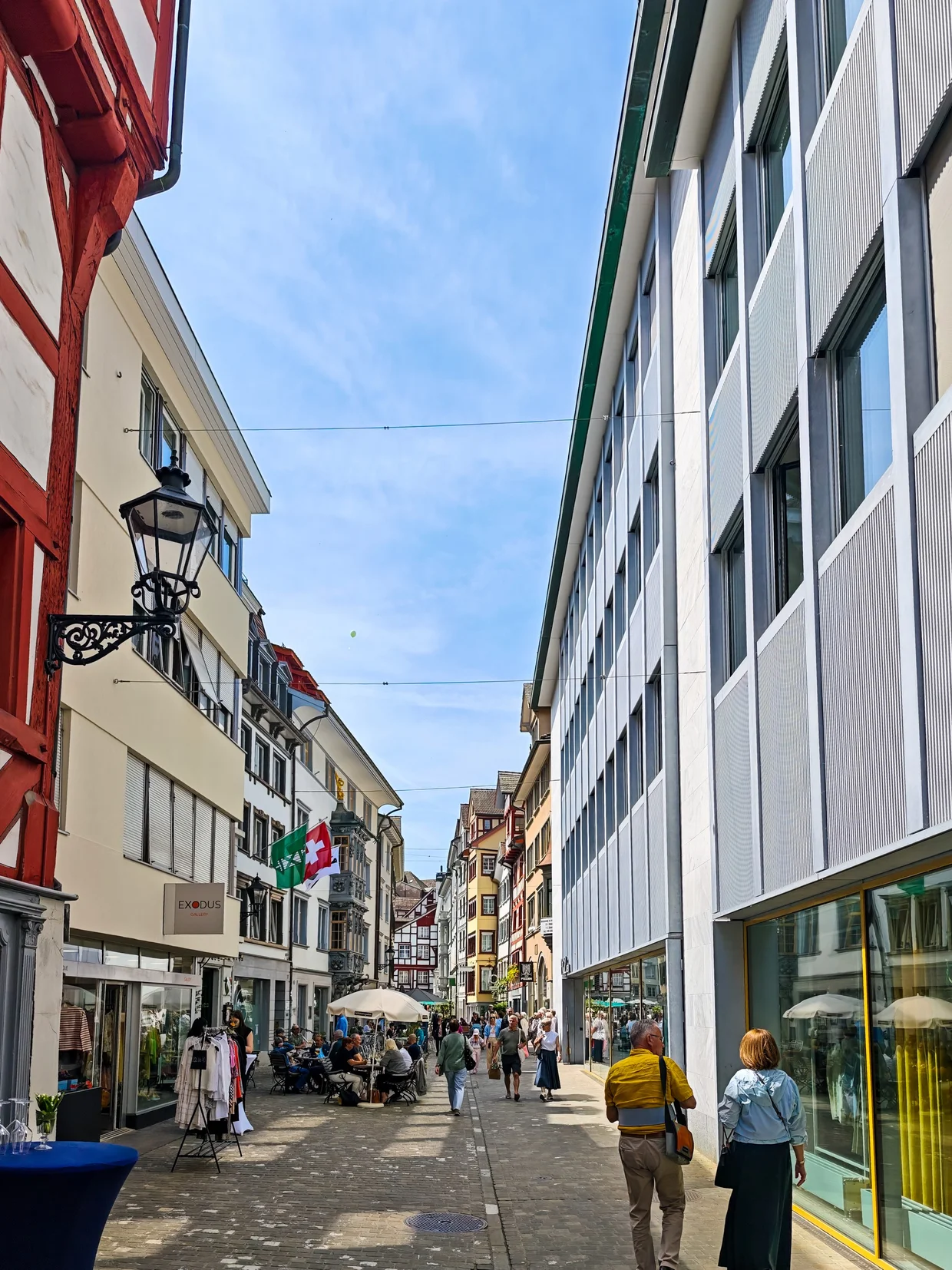 Old town pedestrian street with a half-timbered house and the modern Raiffeisen building beside it