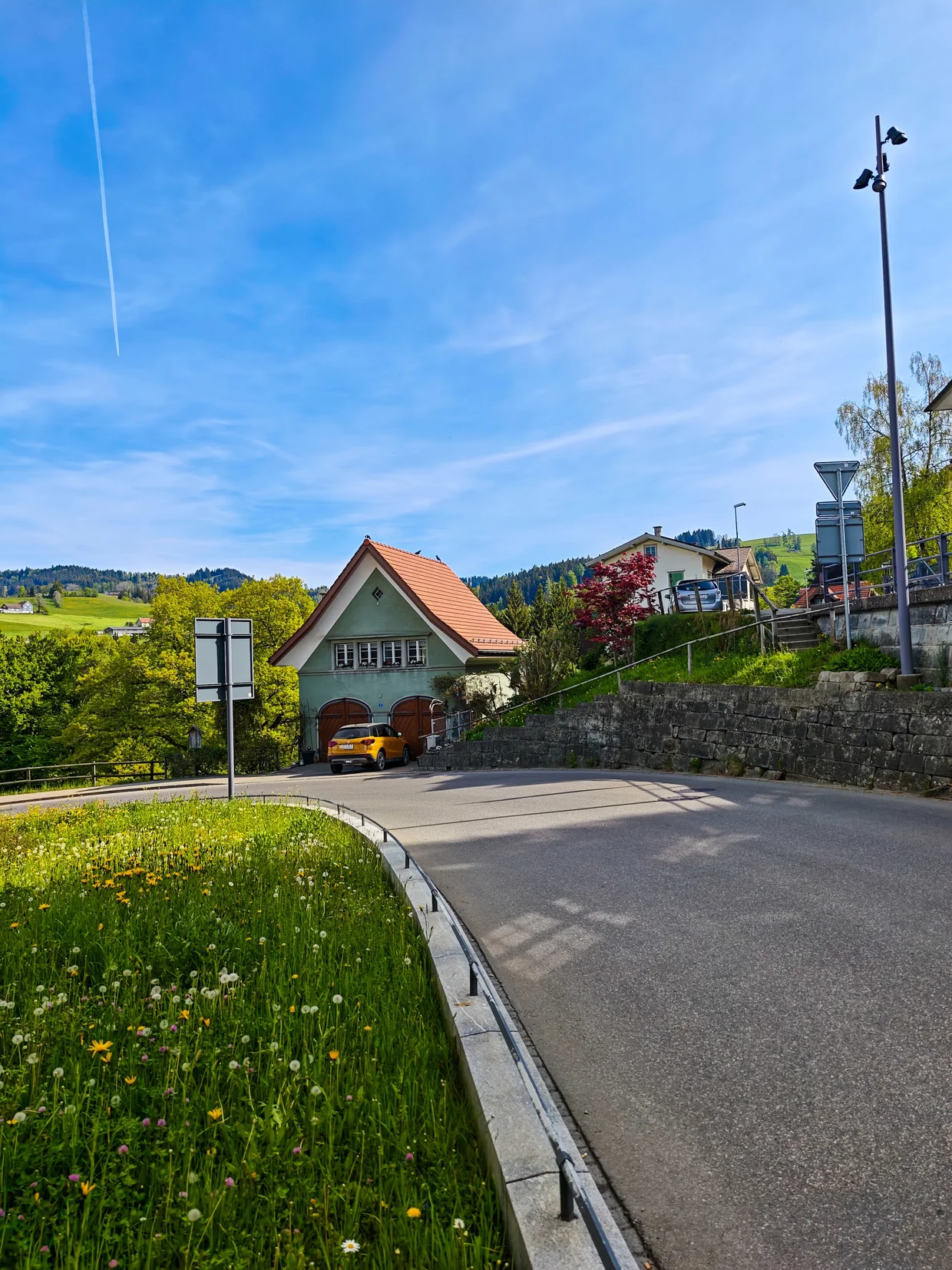 A yellow runabout parked by a green-shuttered Appenzeller chalet on the winding road up into the hills