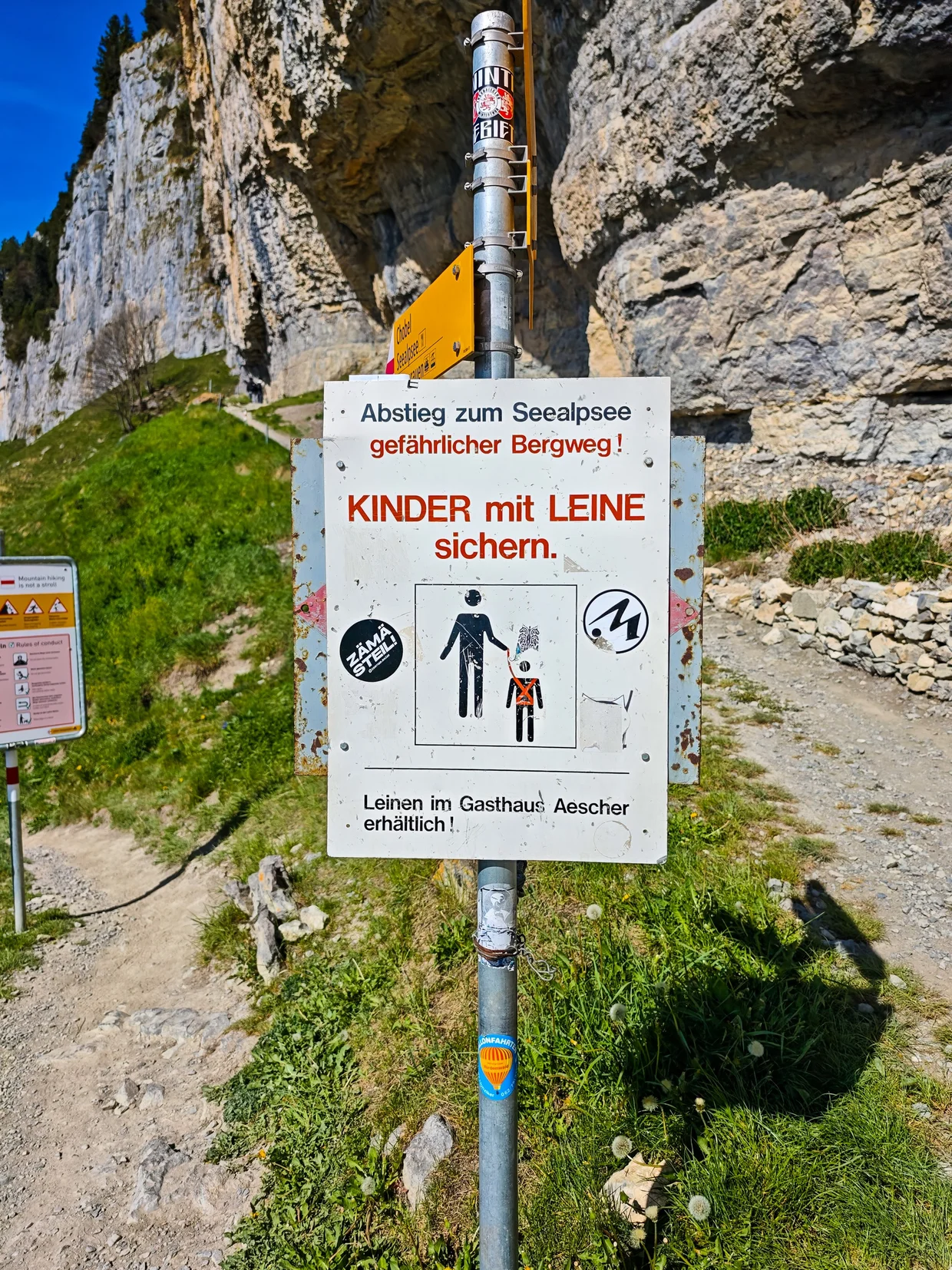 Trail sign warning Kinder mit Leine sichern (Children on leash) at the start of the descent