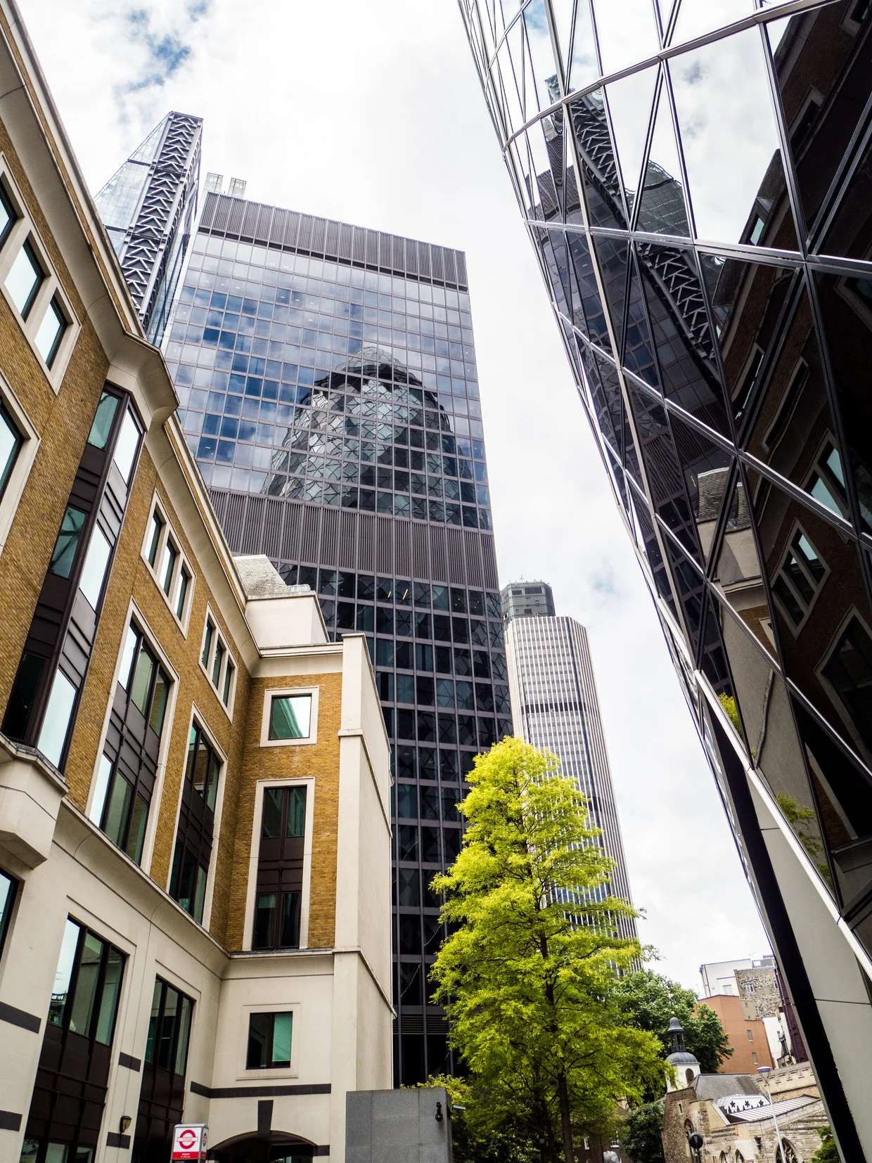 Narrow City lane squeezed between old brick buildings and modern glass towers, the Gherkin reflected in a facade