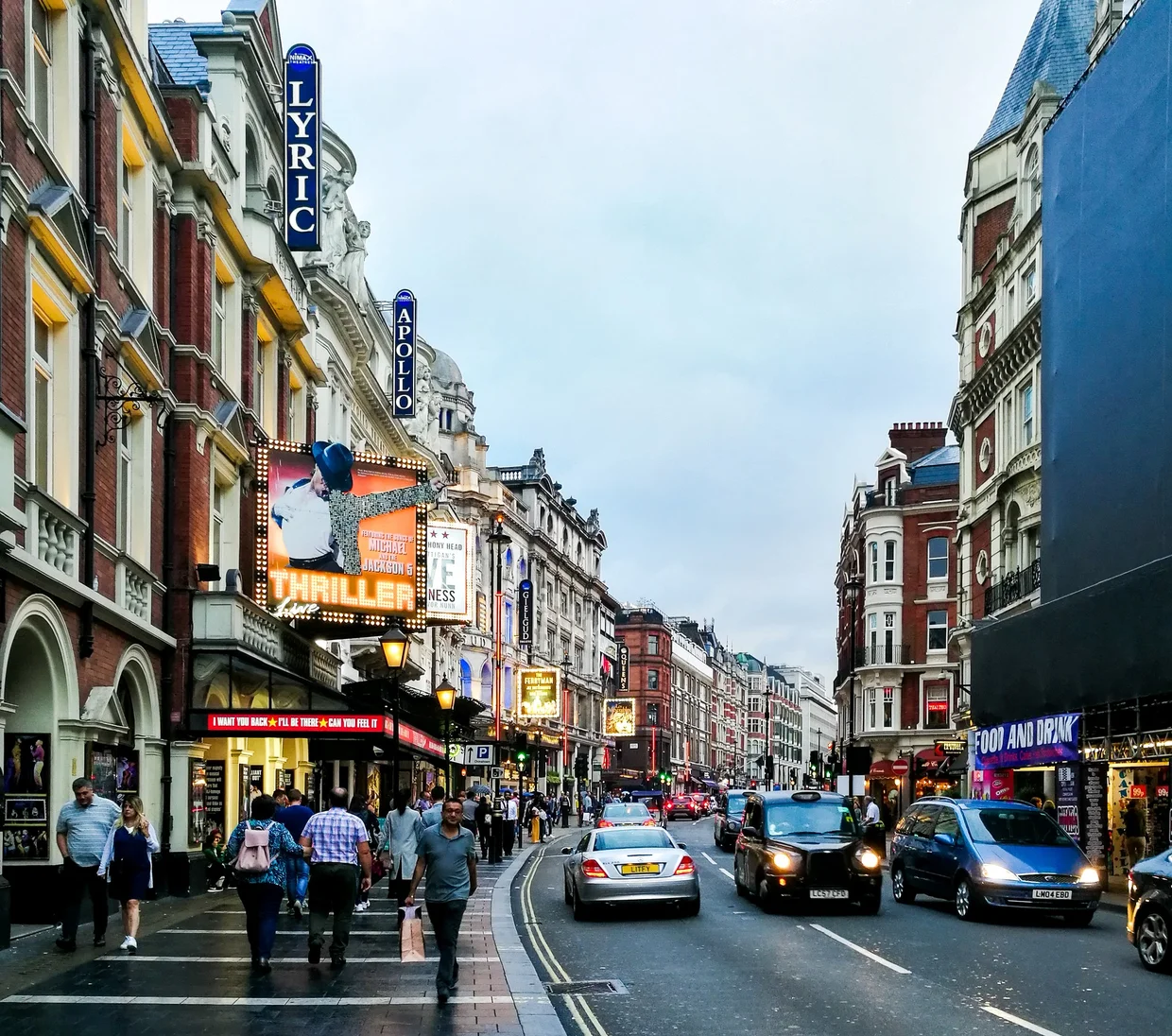 Shaftesbury Avenue at dusk, theatre marquees glowing for the Lyric and other venues