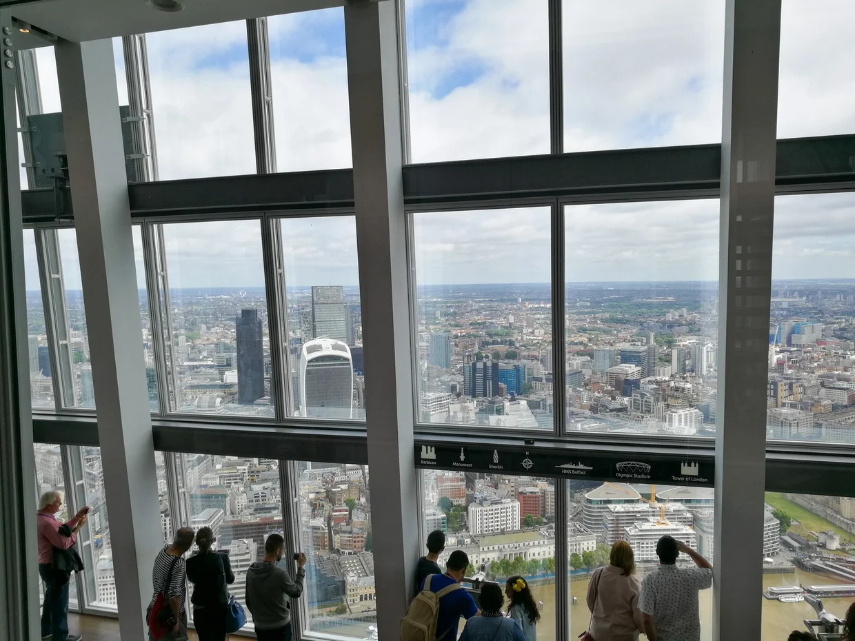 Looking through The Shard's glass walls at the London skyline, visitors taking photos