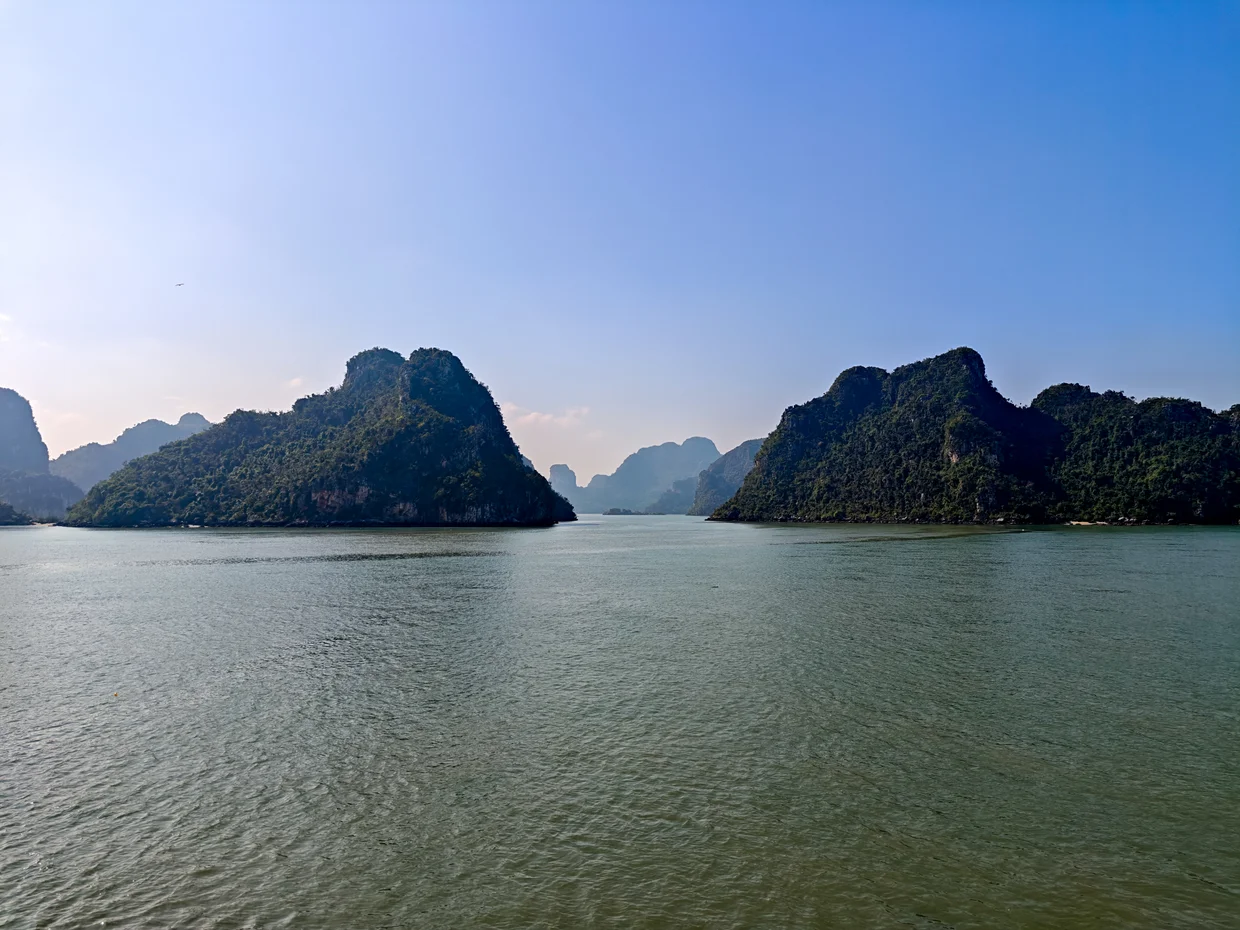 Panoramic view of Ha Long Bay with emerald water and limestone karst islands seen from a cruise boat