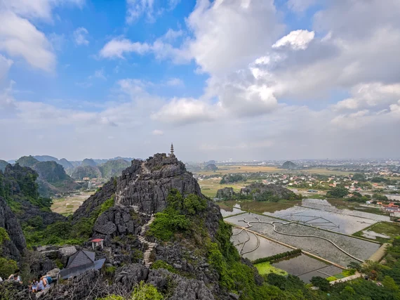 View from Hang Mua ridge with stone steps, karst hills, and rice fields