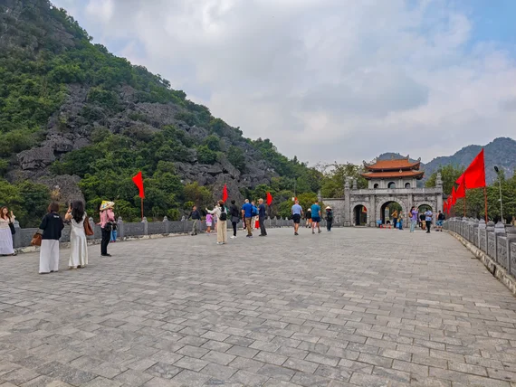 Hoa Lu entrance bridge with red flags and mountain backdrop