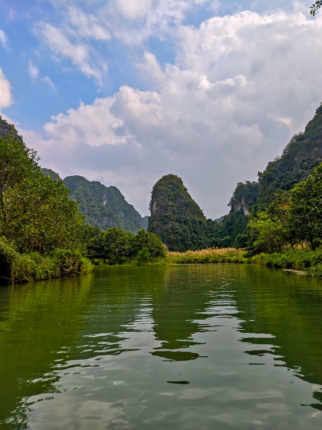 Calm river reflecting limestone karst towers in Ninh Binh