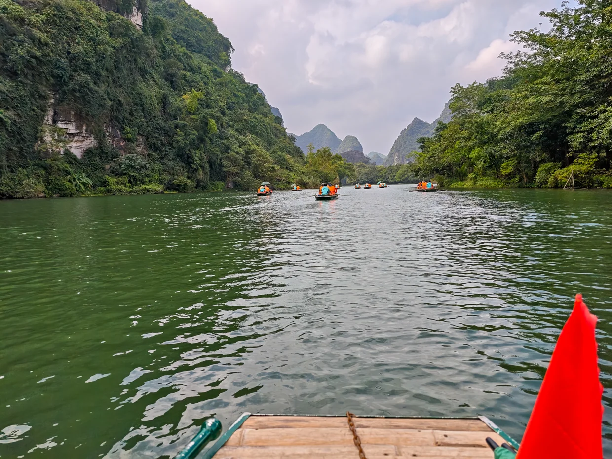 First-person view from a wooden boat approaching limestone karsts on the Trang An river